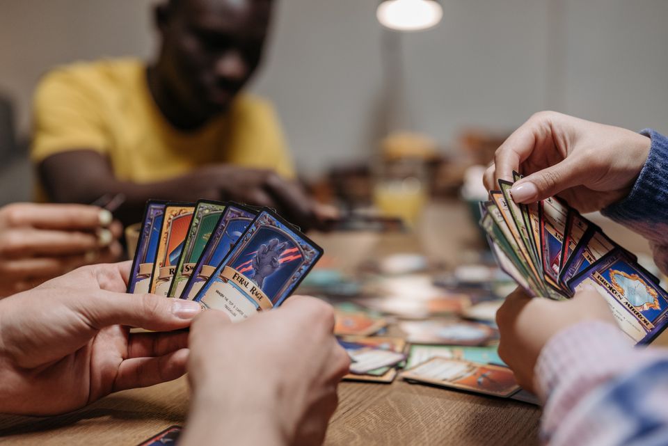 Close-up of adults holding and playing cards together during a card-based trivia game