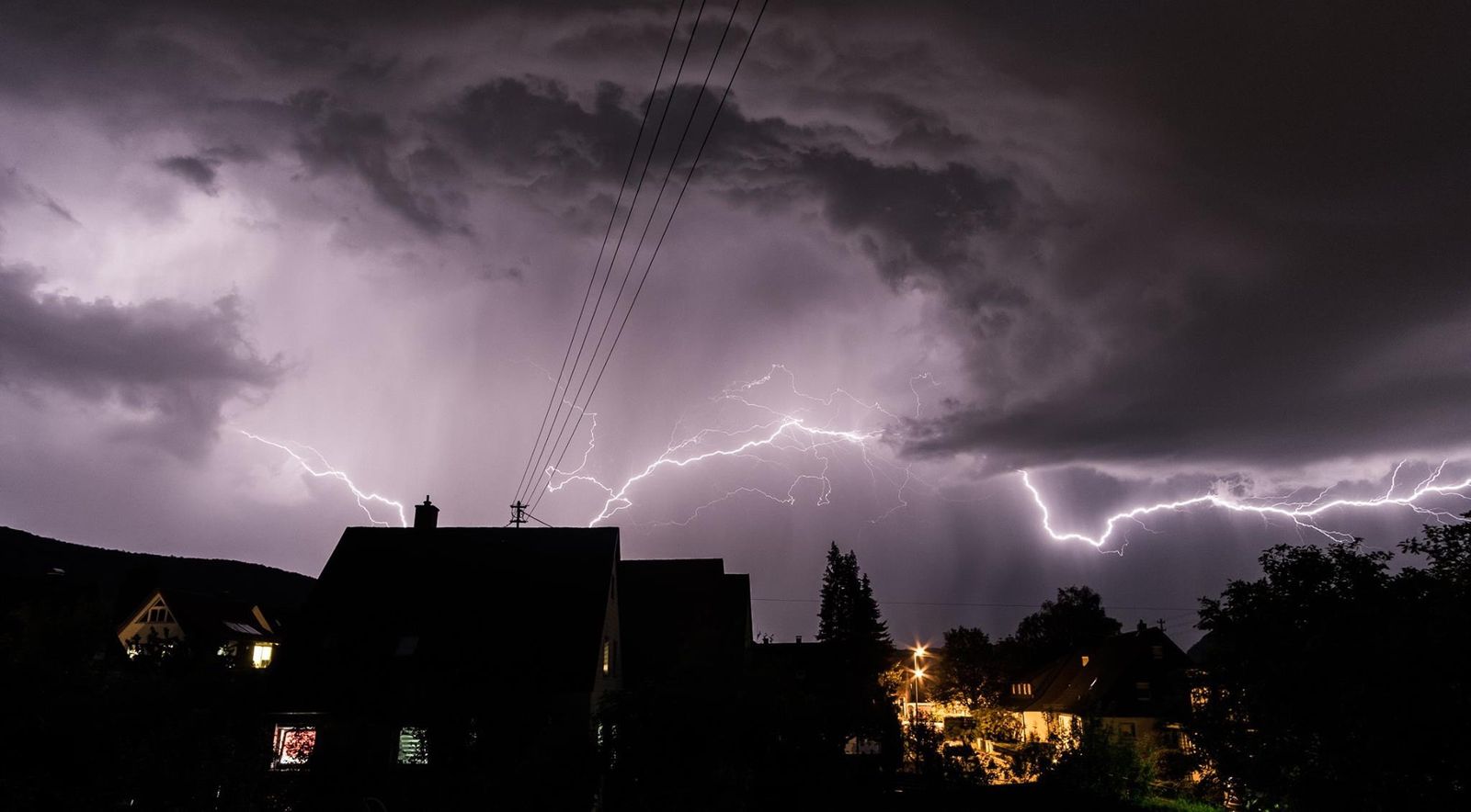Dark storm clouds and lightning over a house, illustrating the kind of severe weather that causes power outages