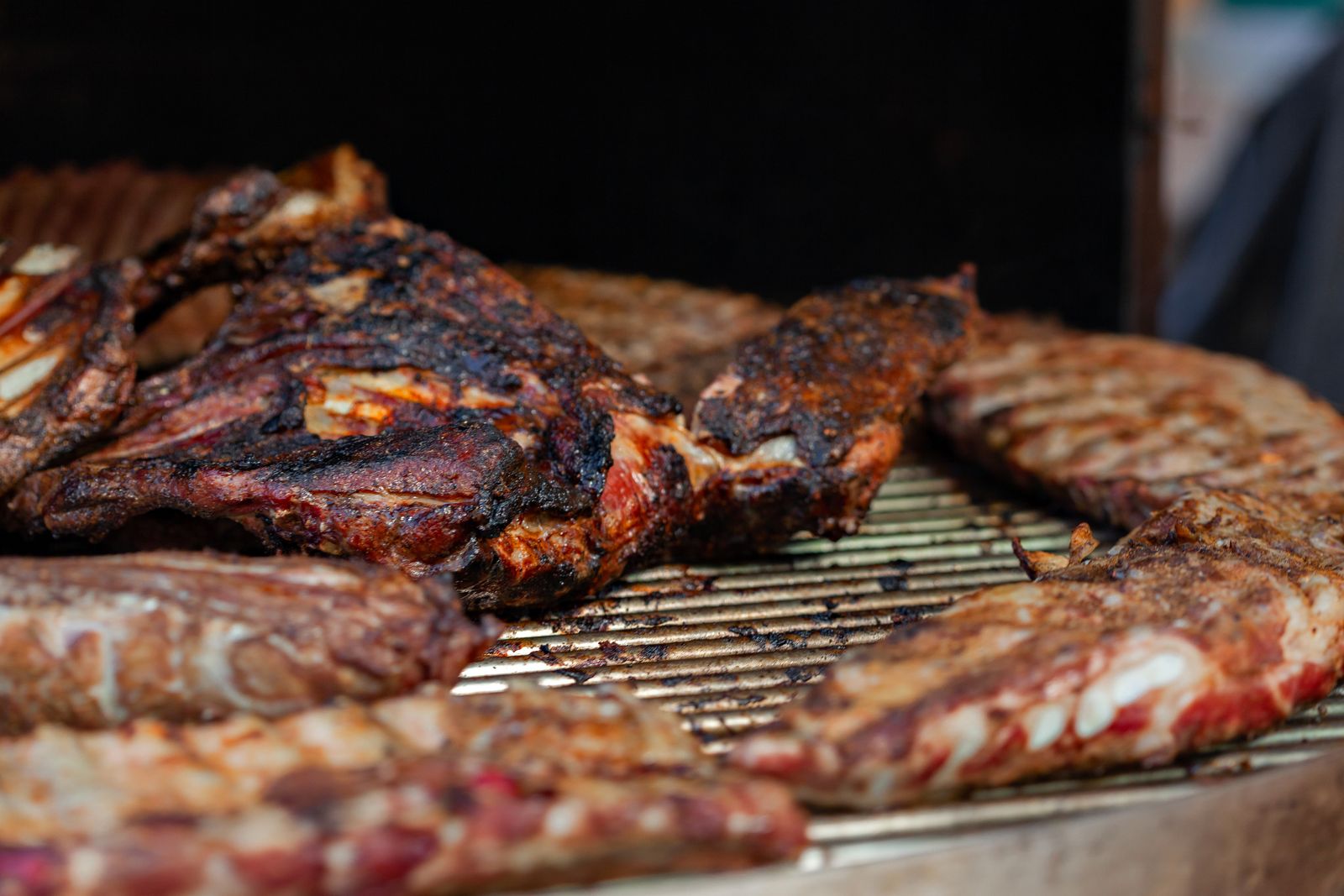 Close-up of juicy grilled and smoked meat with a charred bark on an outdoor grill