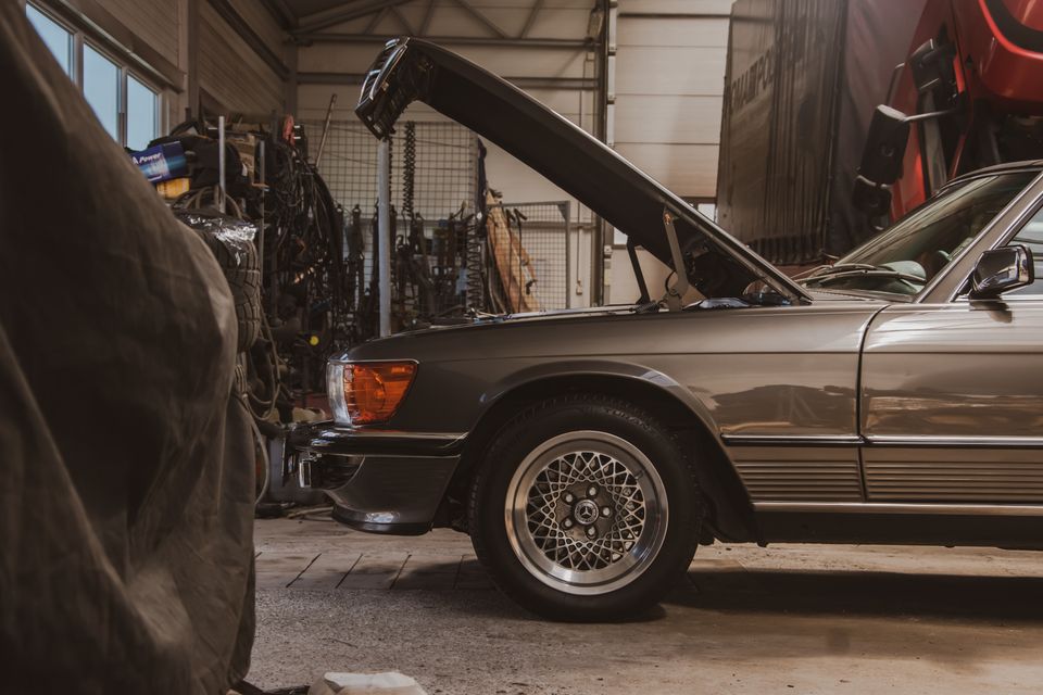 Classic car with its hood open in a home garage, the kind of seasonal vehicle that benefits from a battery maintainer during long storage
