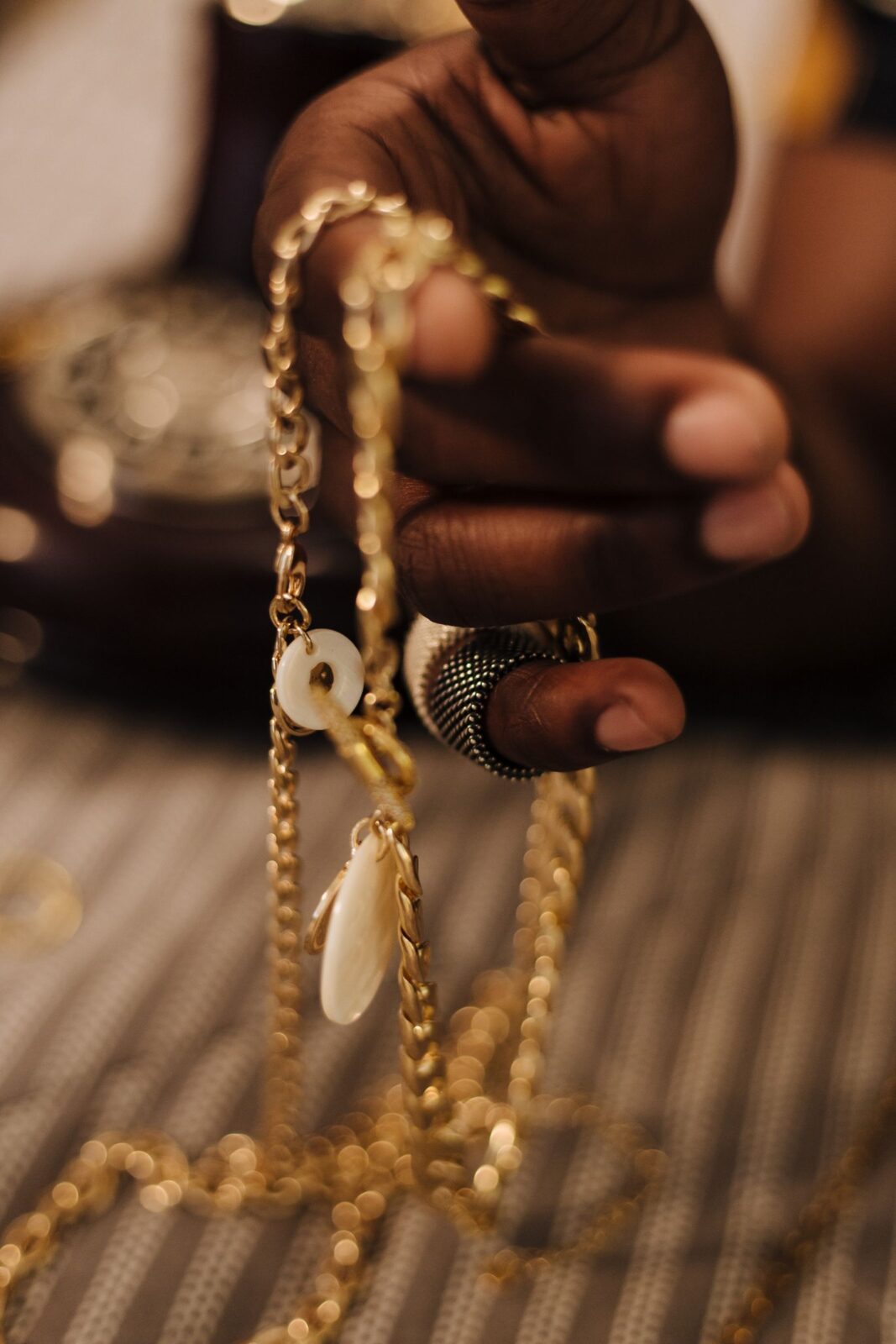 Close-up of a hand holding a delicate gold necklace chain