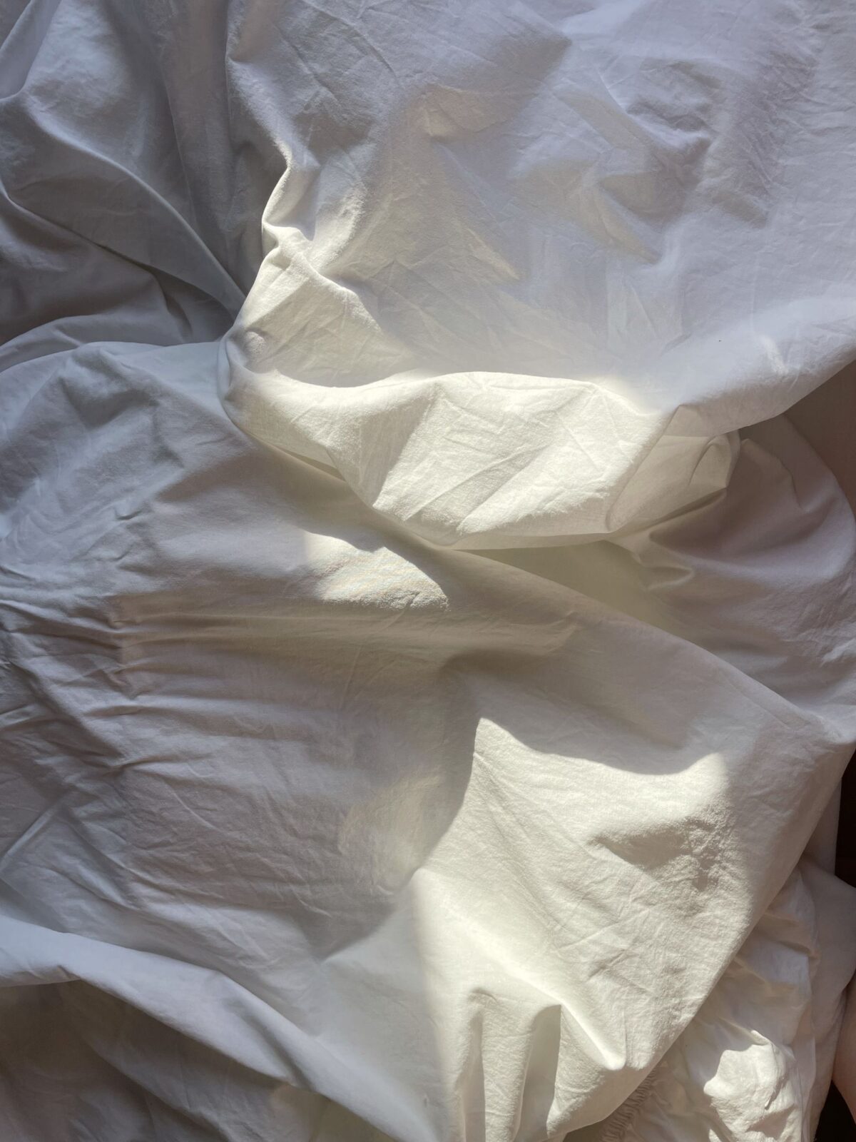 Close-up of a crisp, creased white cooling bed sheet showing weave texture