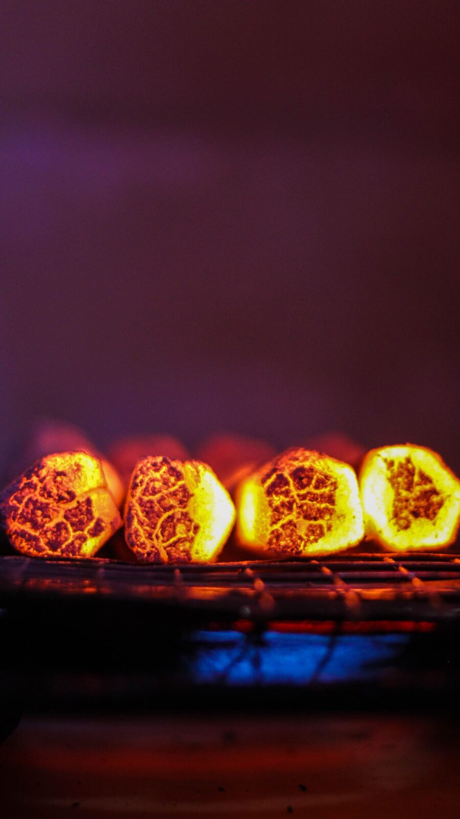 Close-up of glowing hot charcoal briquettes on a grill grate