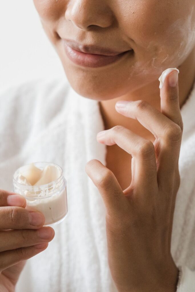 Close-up of a person applying a rich, unbranded facial cream to her cheek