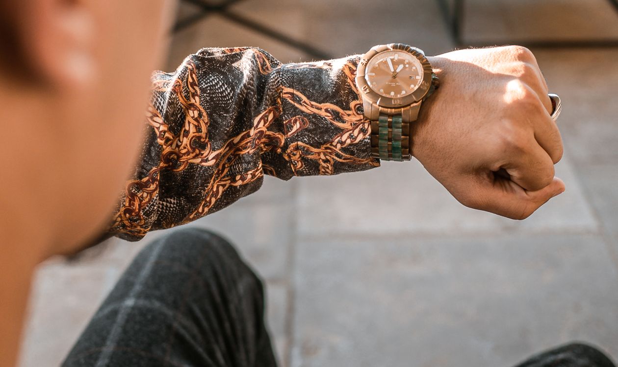 Person checking the time on a wristwatch outdoors in sunlight
