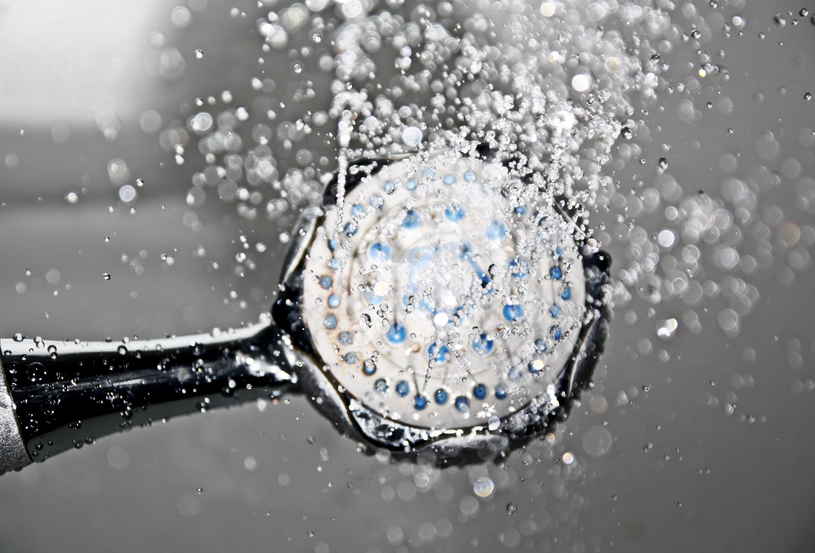 Black wall-mounted shower head switched on with water running