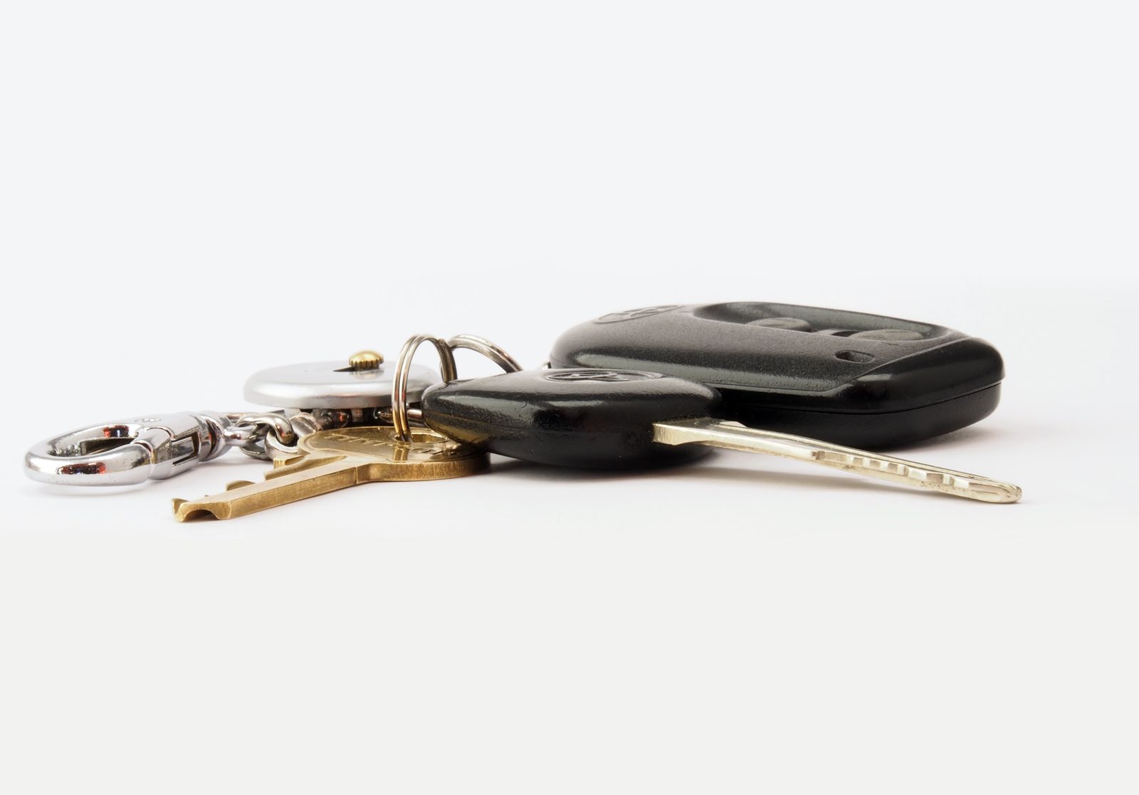 A set of car keys with a key fob on a ring, lying on a white surface