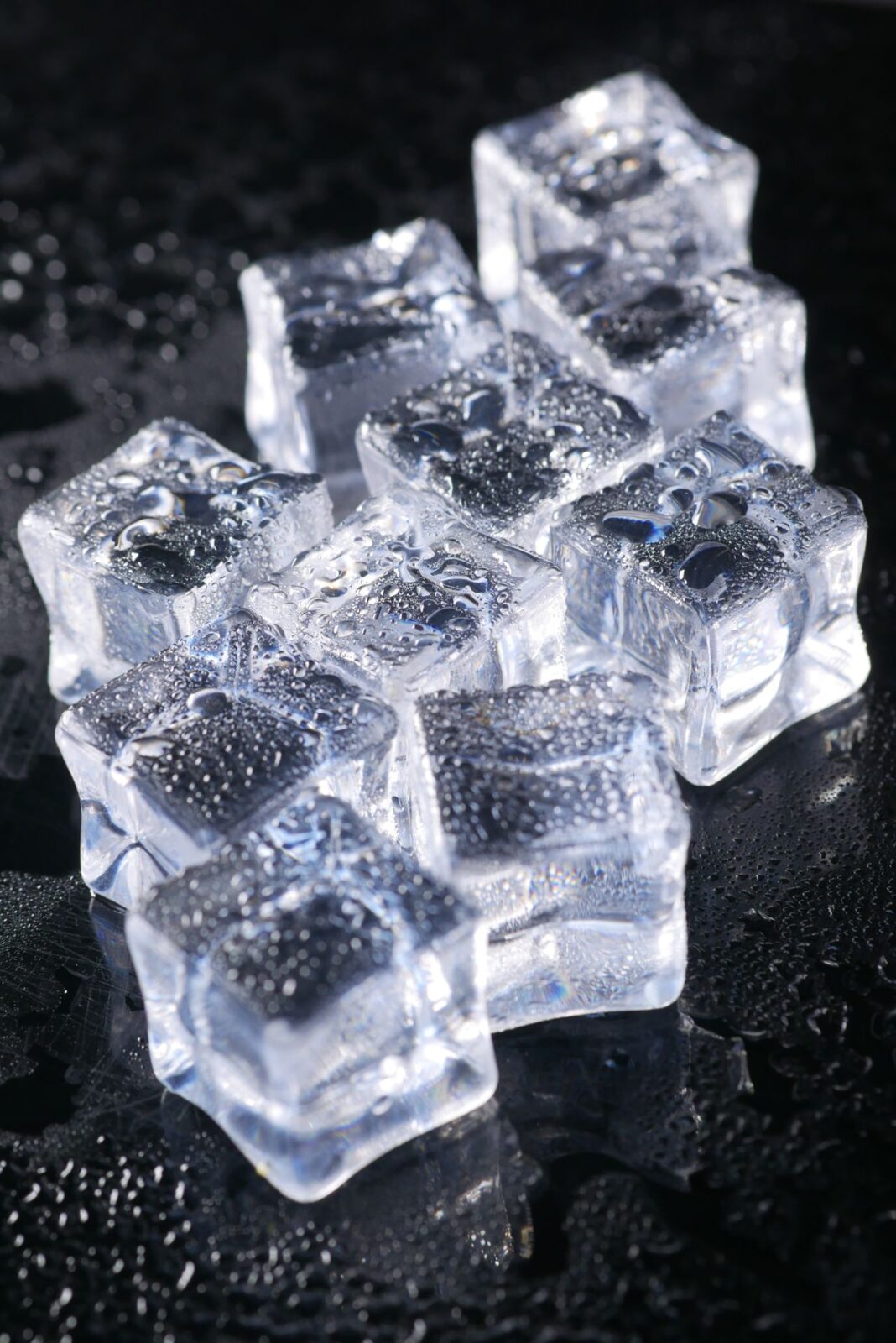 A pile of clear ice cubes on a dark surface