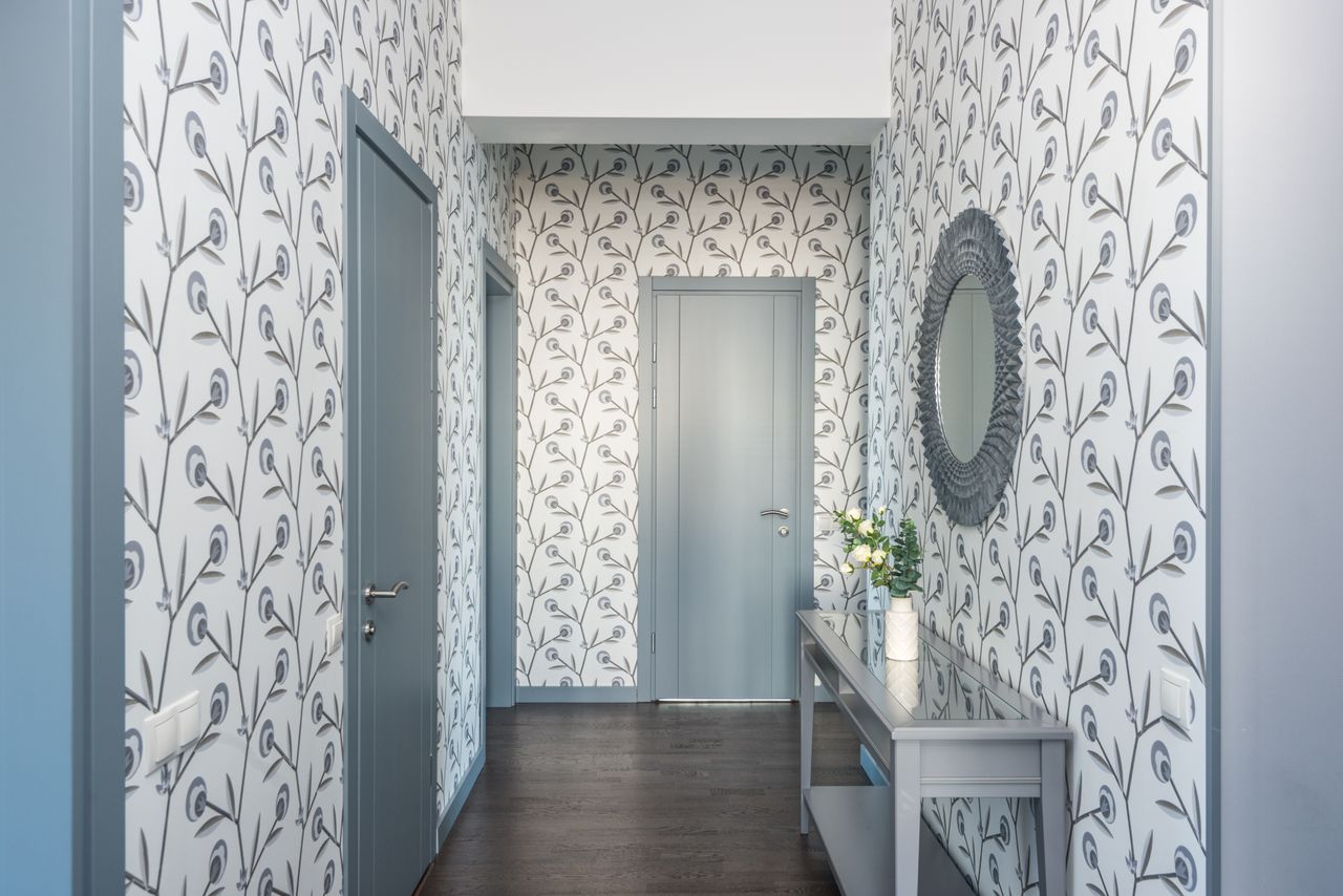 A narrow hallway with gray and white patterned wallpaper on both walls