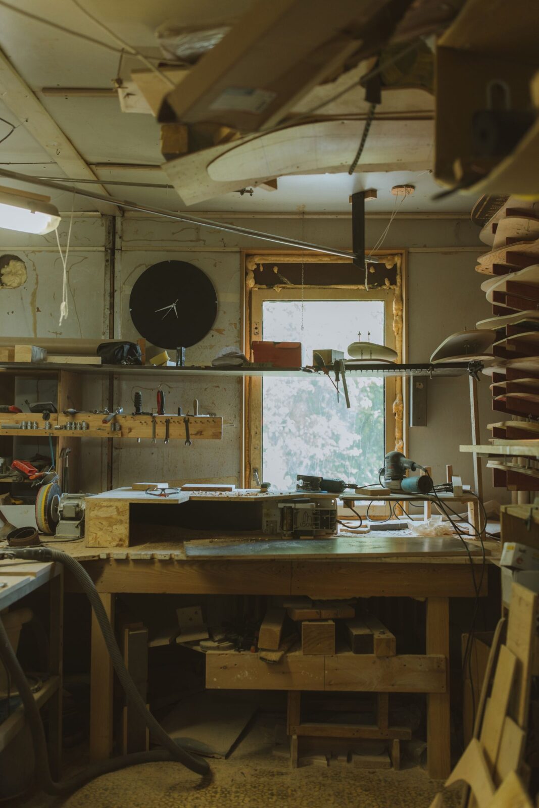Home woodworking shop with a long workbench, a wall rail of hand tools and a window at the back