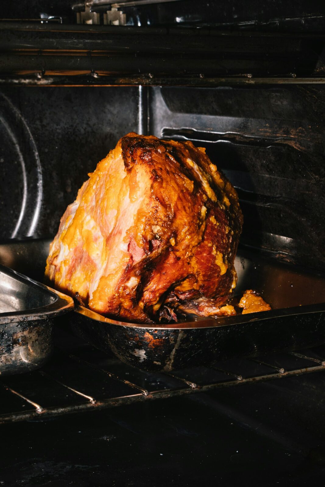 Roast ham in a dark metal pan sitting on an oven rack