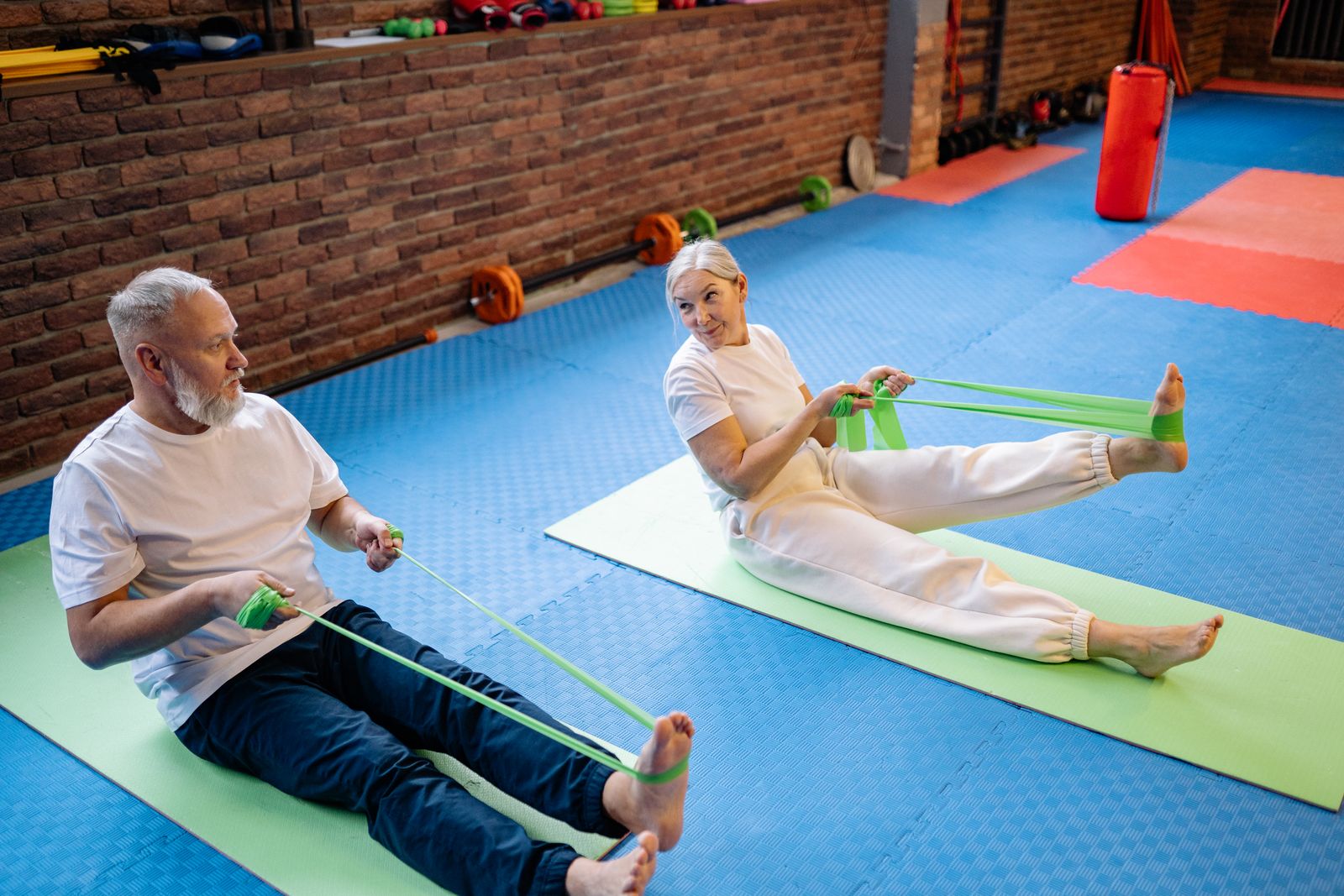 Two people doing a resistance band workout together on yoga mats indoors