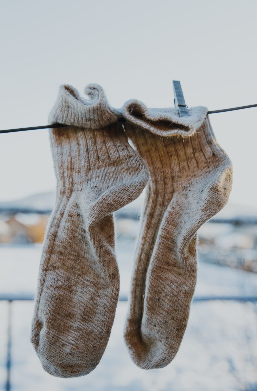 Pair of gray wool socks pinned to a clothesline outdoors in winter