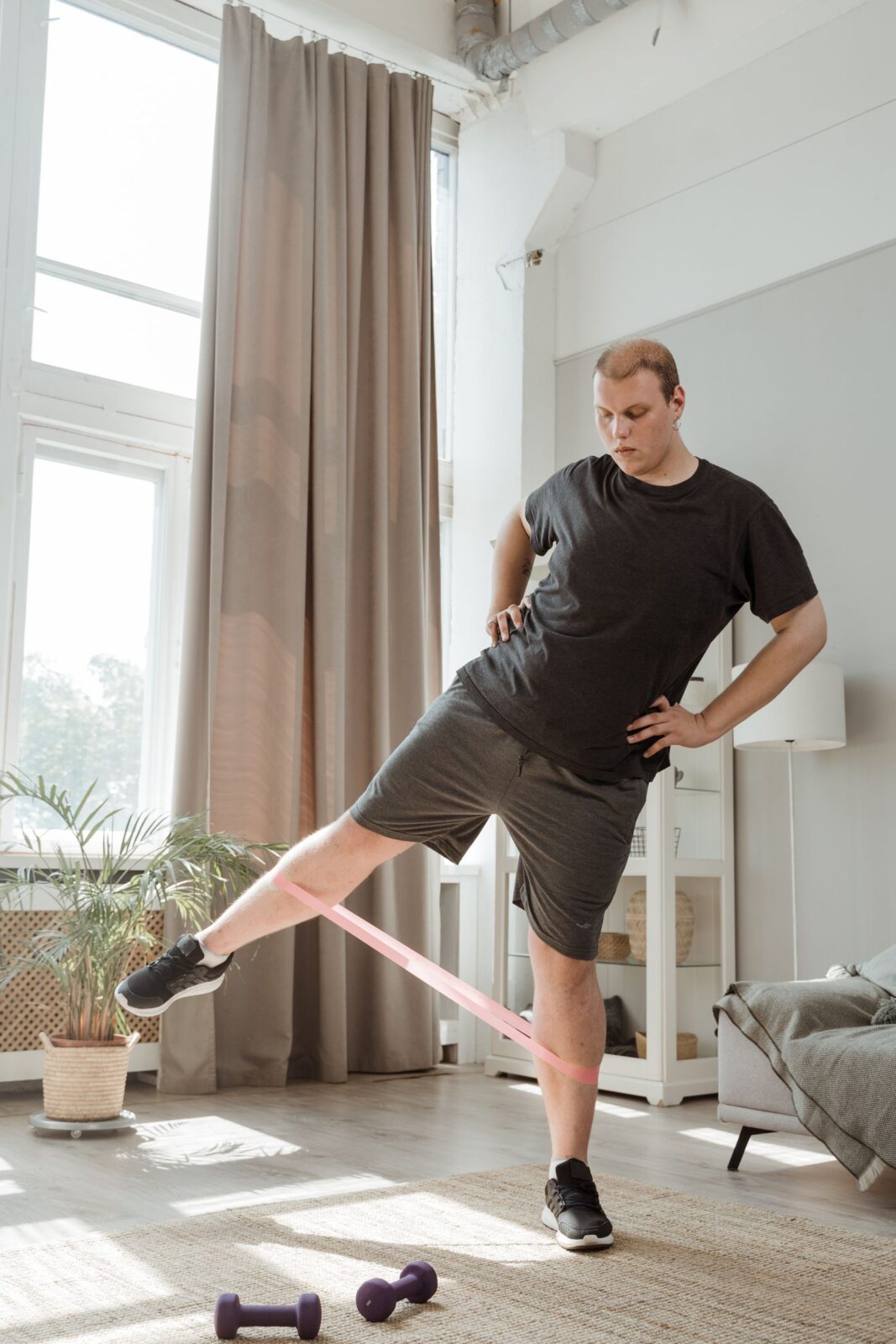 Man performing a standing leg exercise with a resistance band in a home living room