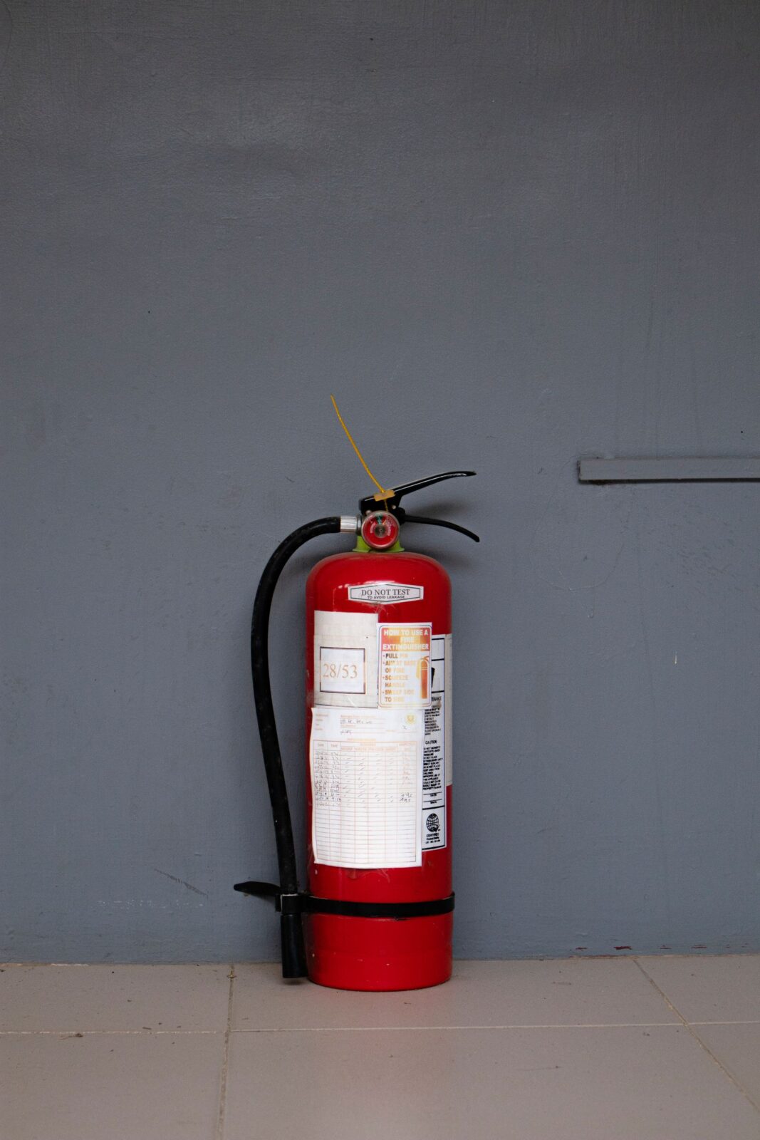 Red fire extinguisher standing against a gray wall