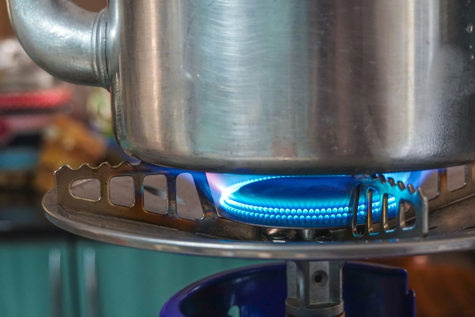 Stainless steel pot sitting over a lit blue gas burner flame