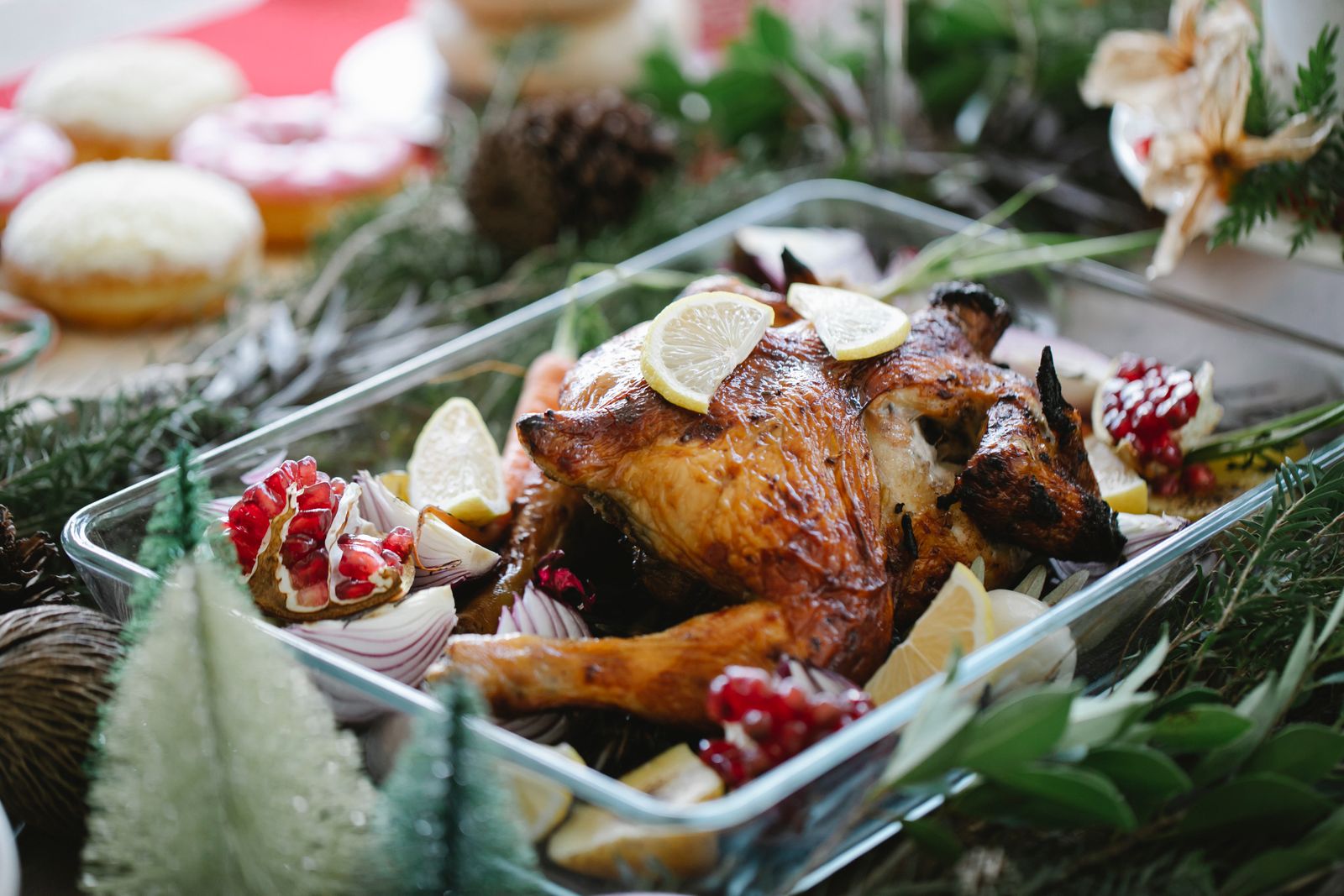 Whole roasted turkey in a rectangular glass baking dish with lemon slices and pomegranate seeds