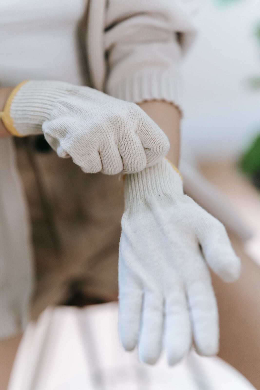 Hands pulling on white knitted gloves
